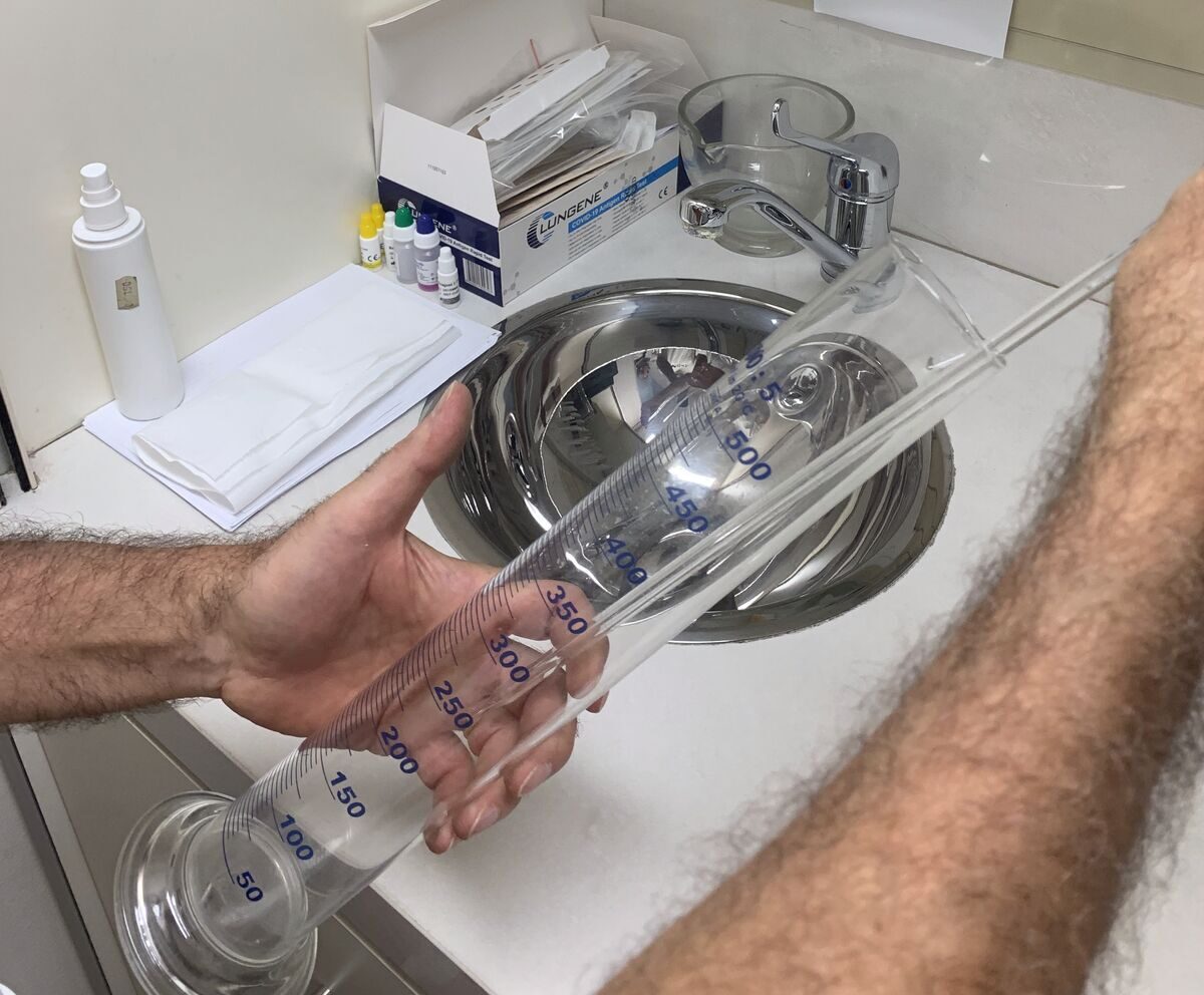Le mani di un farmacista sciacquano un cilindro graduato nel laboratorio galenico