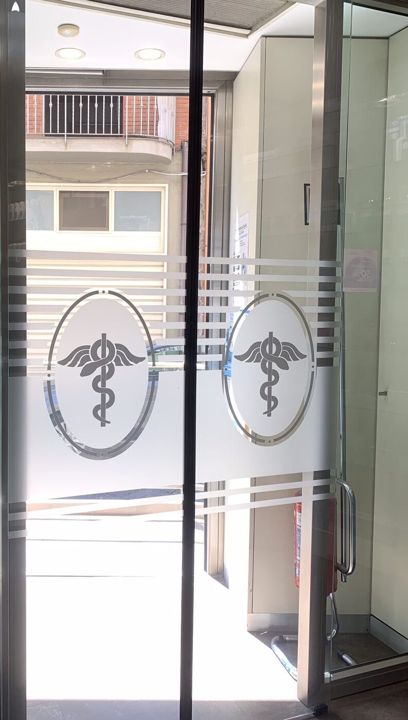 Le porte a vetri della farmacia viste dall’interno, con due caducei incisi sul vetro satinato