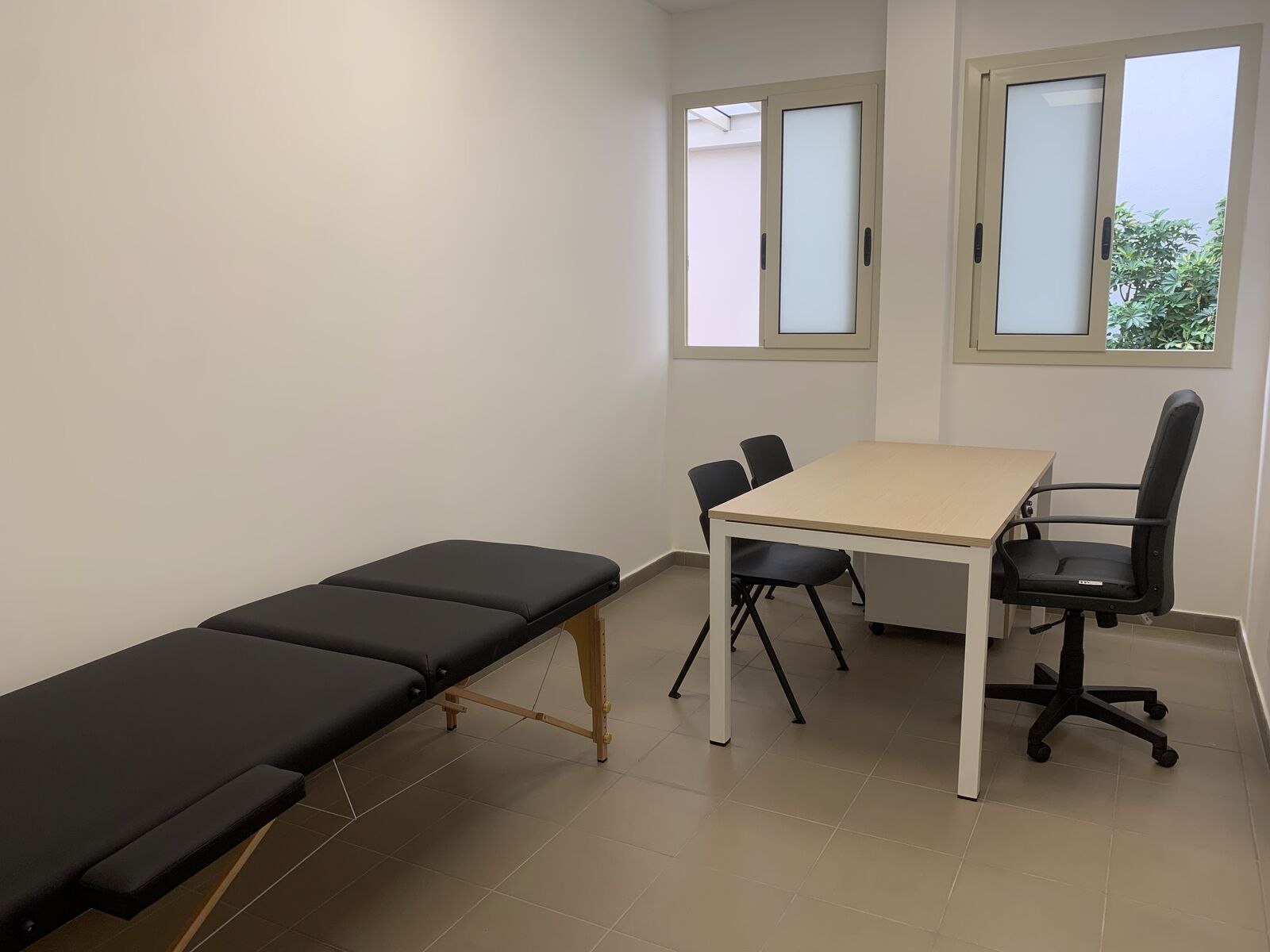 Seconda stanza dell’area servizi con lettino e scrivania, illuminata da due finestre