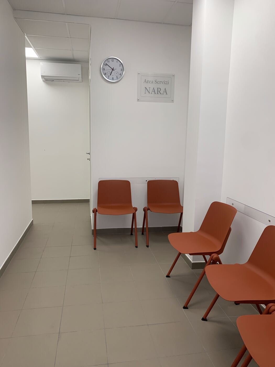 La sala d’attesa dell’area servizi, con le sedute e l’orologio a parete